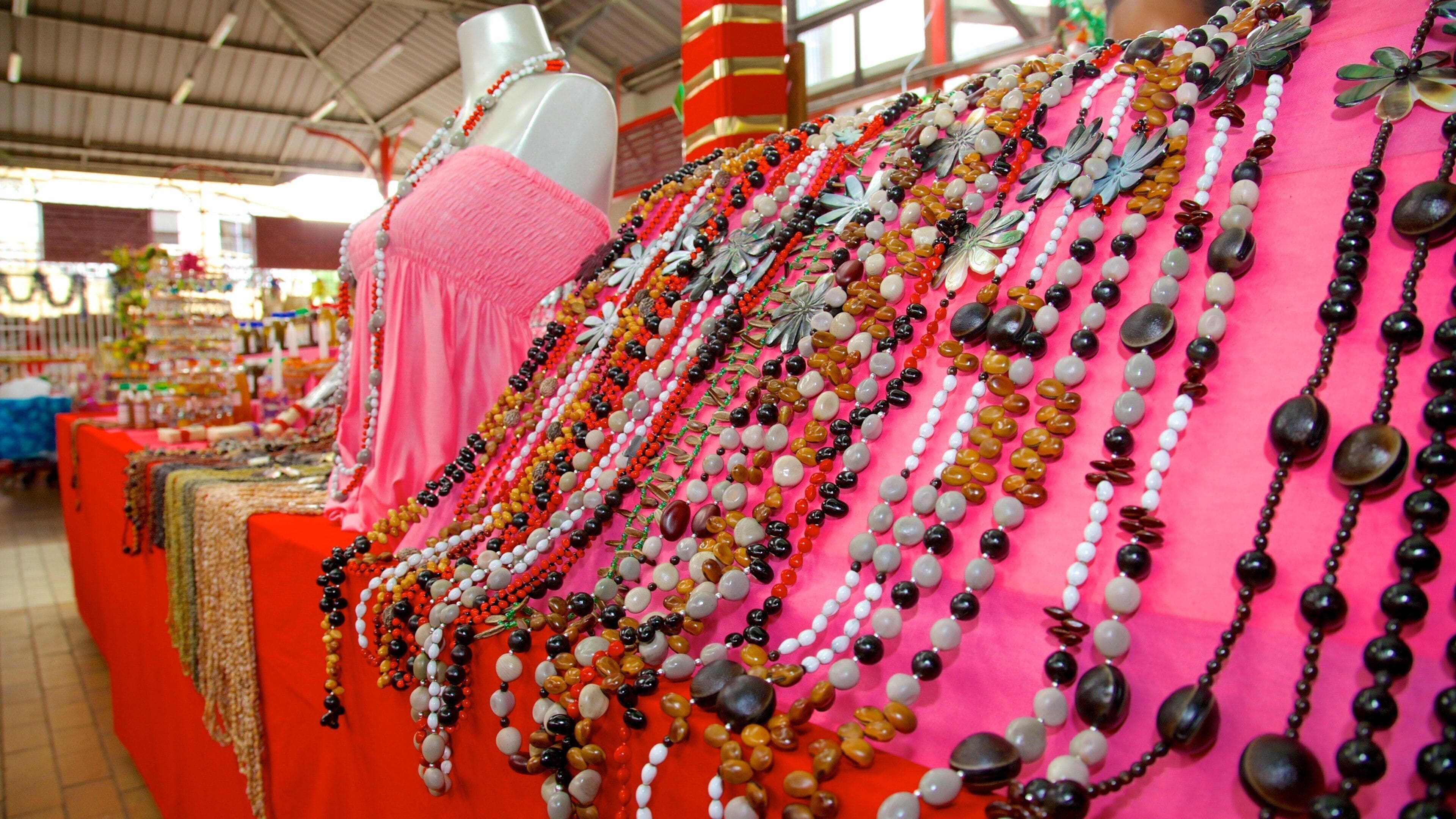 Une variété de colliers colorés sont exposés sur une table dans un marché.