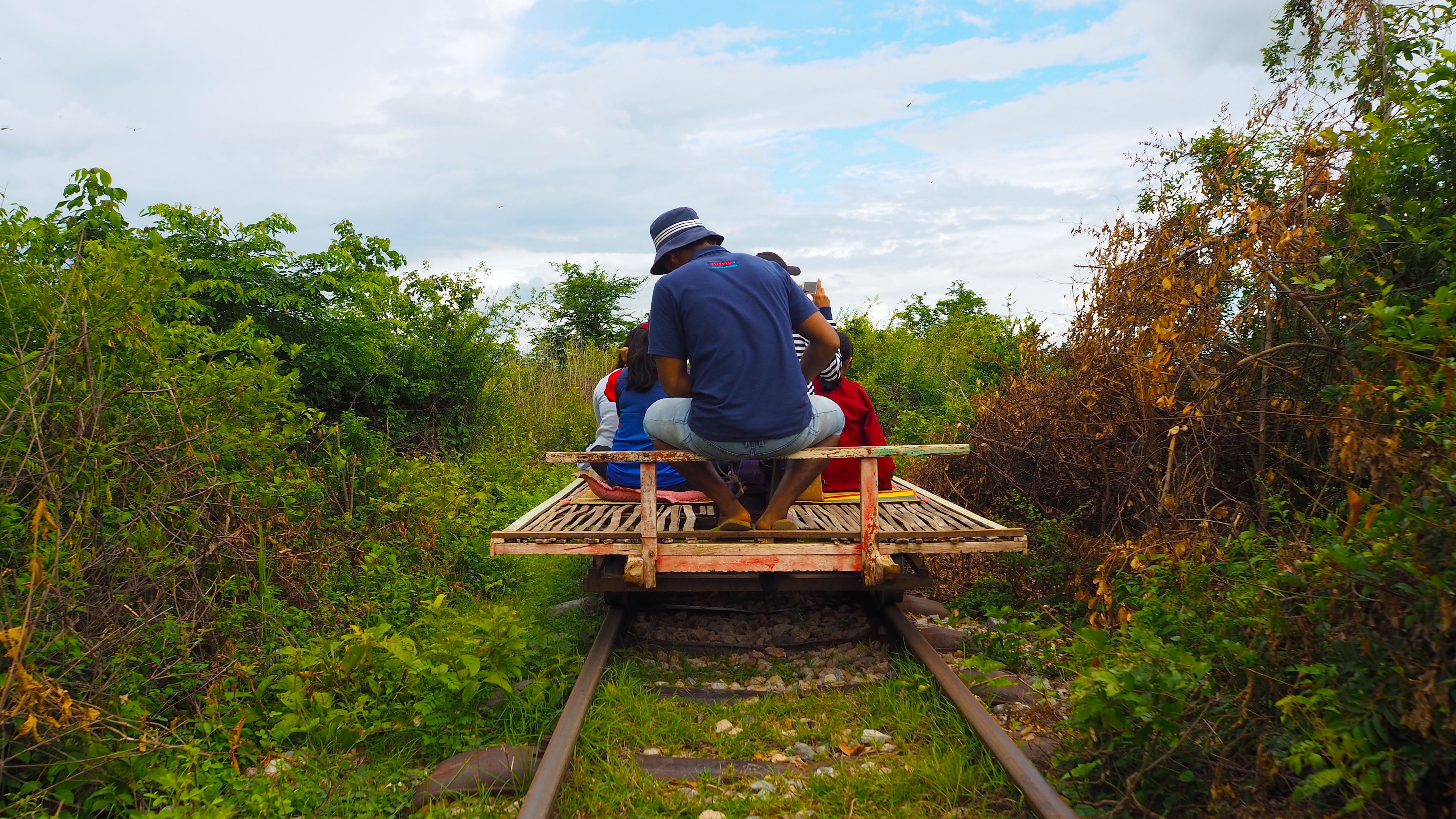 Um trem com passageiros sentados numa plataforma de madeira.