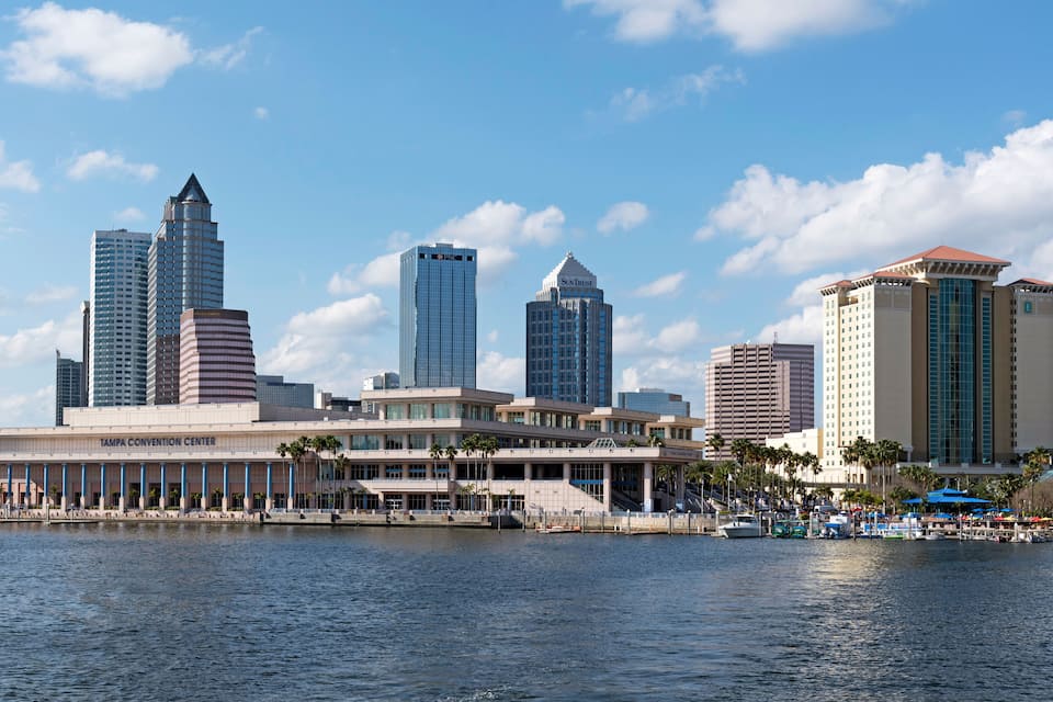 Paisatge urbà al costat del mar amb edificis destacats, incloent el Centre de Convencions de Tampa i diverses estructures elevades.