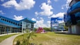 A modern building with blue glass windows, a playground with purple slides, and a blue climbing structure.