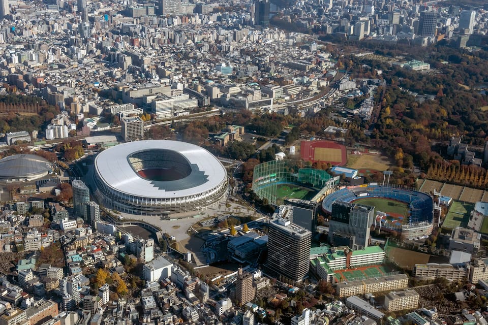 Luchtbeeld van een stad met een groot stadion, omringd door gebouwen en een sportveld.