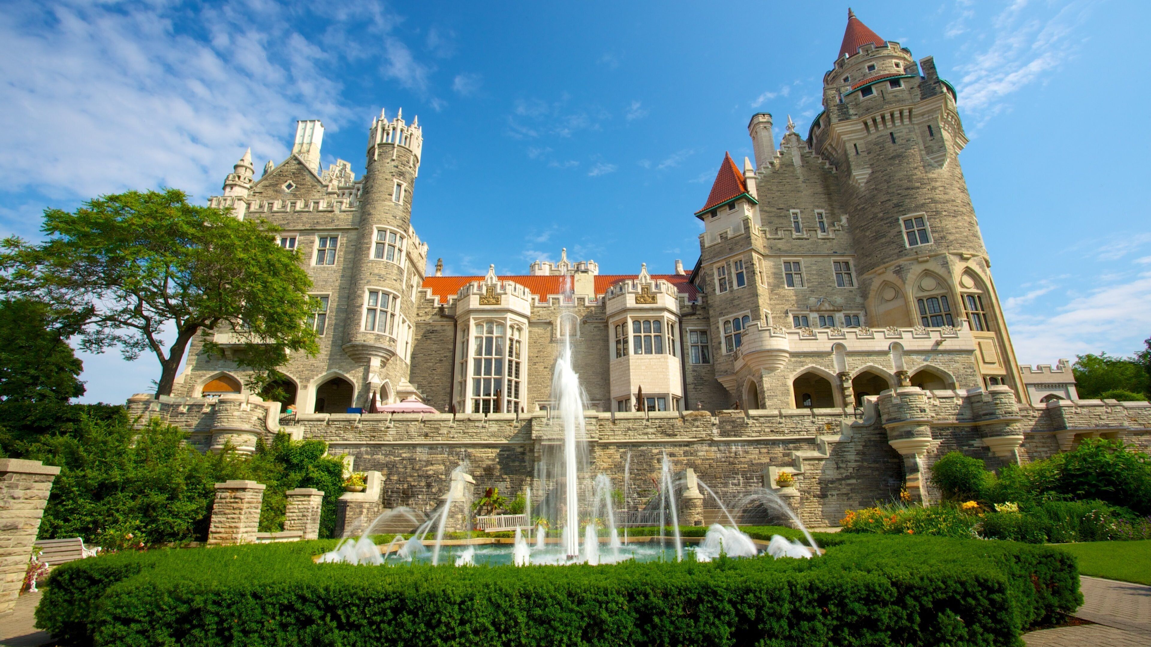 A large castle with a fountain in front.