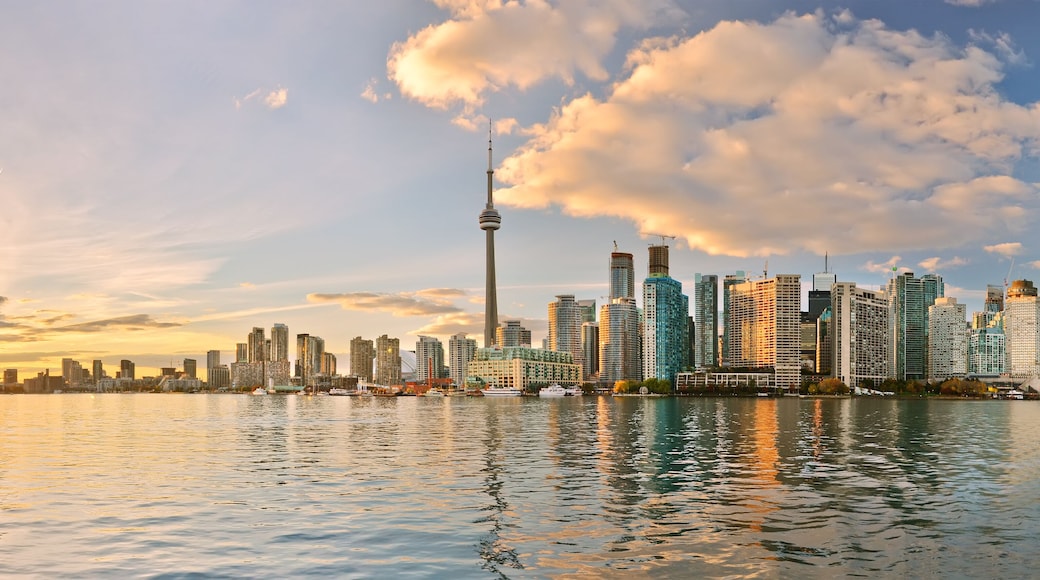 A city skyline with a prominent tower, reflecting on calm water during sunset.