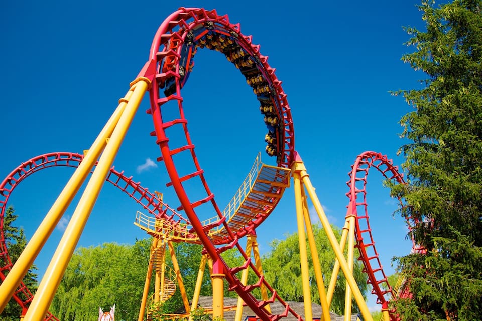 A roller coaster with red tracks and yellow supports.