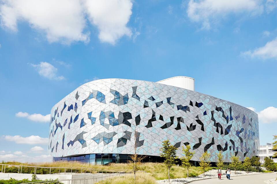 A modern building with a geometric facade and a clear blue sky.