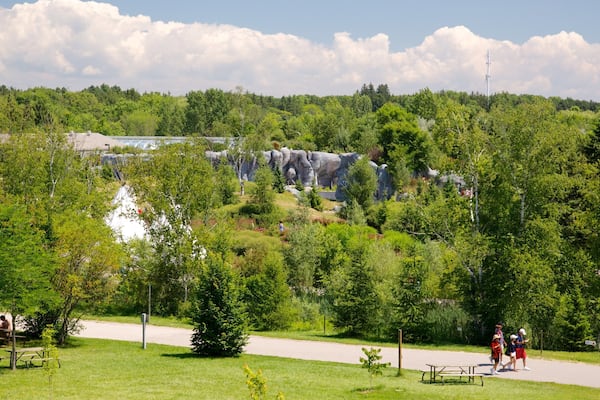 Ein Park mit einer großen Felsformation, Picknicktischen und einem Fußweg.
