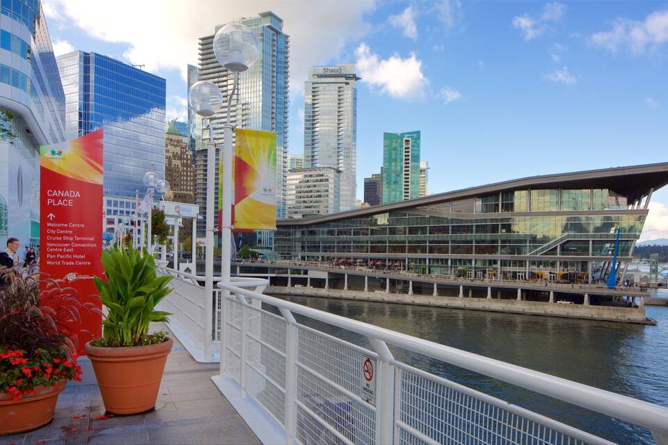 Un paseo marítimo con edificios modernos, una estructura de vidrio y un cartel que indica Canada Place.