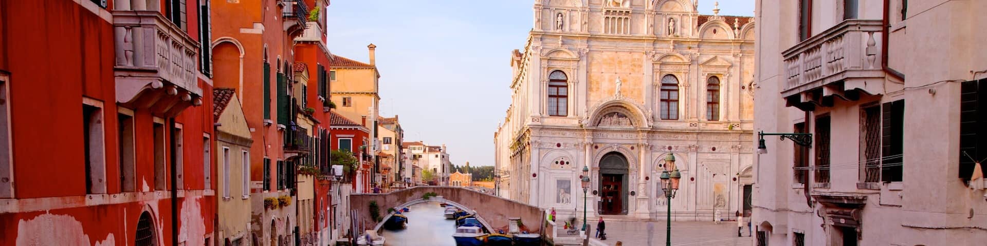 A narrow canal in Venice, Italy, lined with colorful buildings and boats.