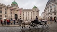 A historic building with ornate architecture and a horse-drawn carriage in front.