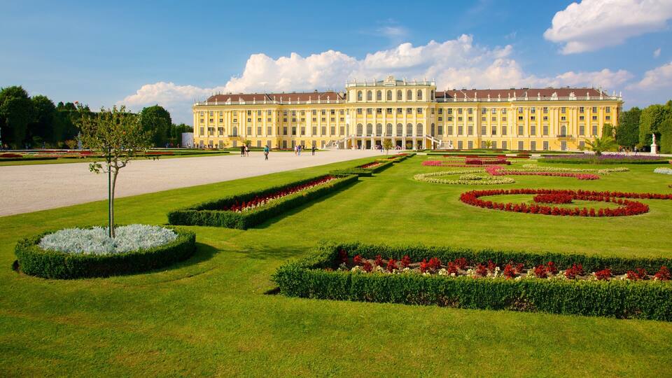 Um palácio imponente com jardins simétricos e relvados bem cuidados.