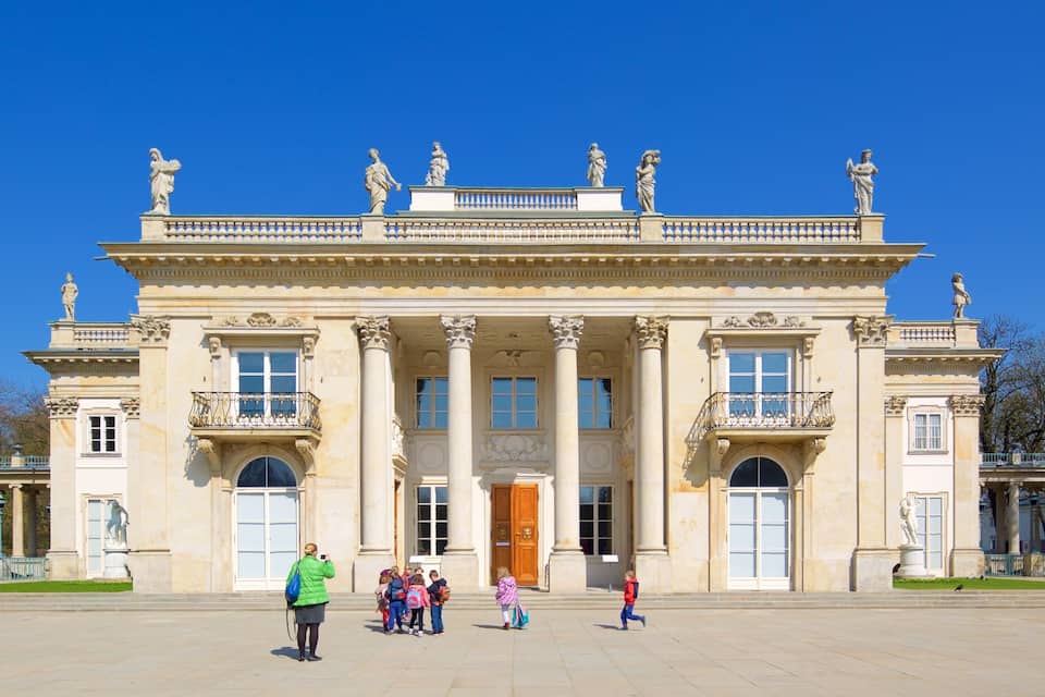 A grand neoclassical building with statues, columns, and ornate balconies.
