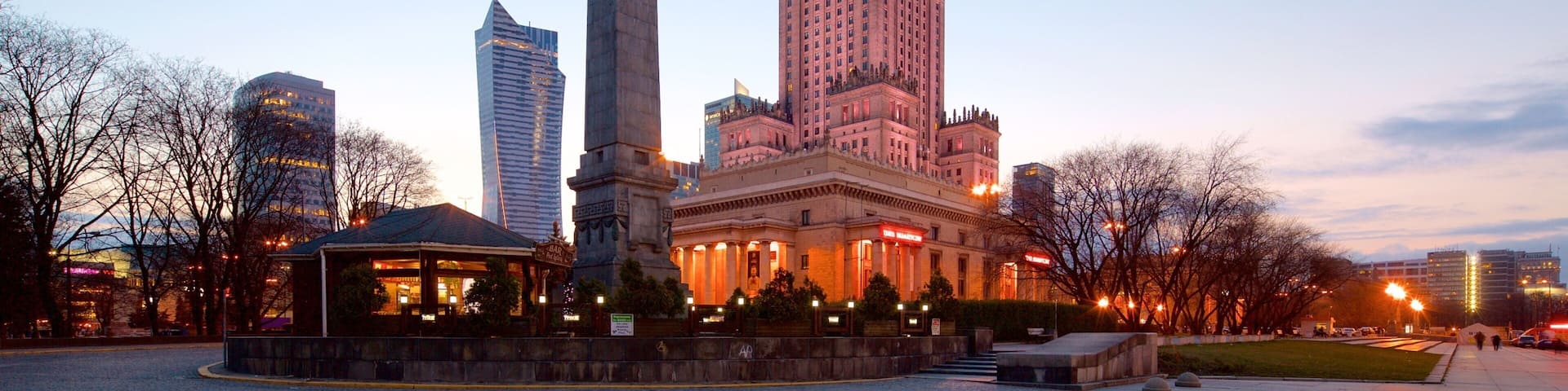 A historic building with a tall tower and an obelisk in a city square.