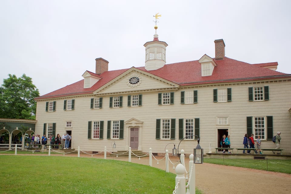A historic building with a red roof, green shutters, and a weather vane.