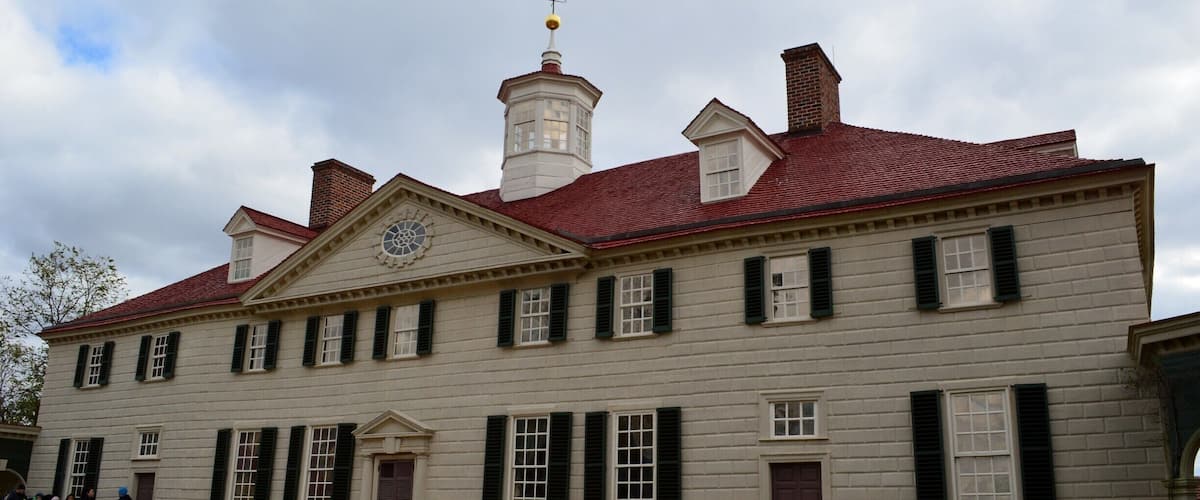 A historic building with a red roof, white walls, and green shutters.