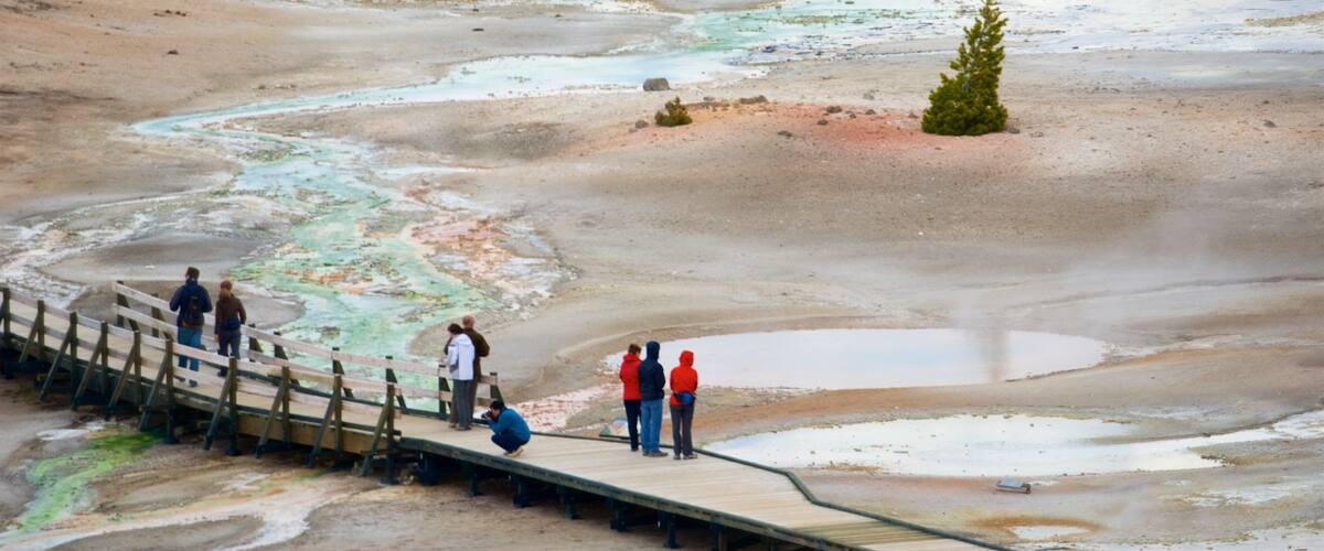 Norris Geyser Basin das einen heiße Quelle und Brücke sowie kleine Menschengruppe