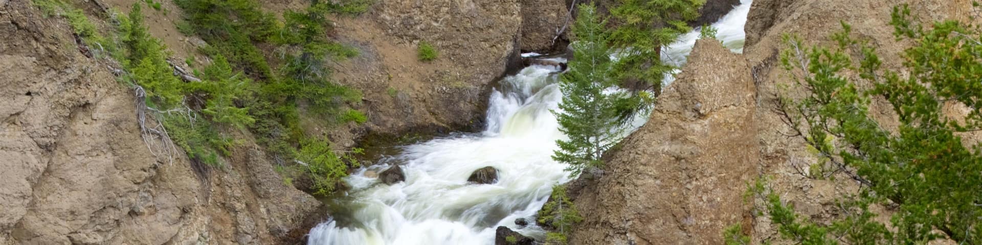 A waterfall cascading down a rocky cliff surrounded by green foliage.