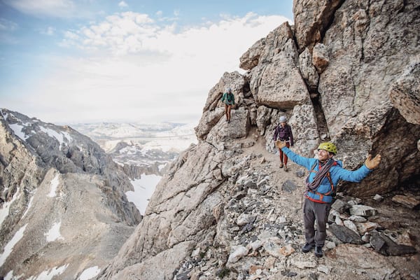 Climbing guide spreads his arms in wonder while taking in the view