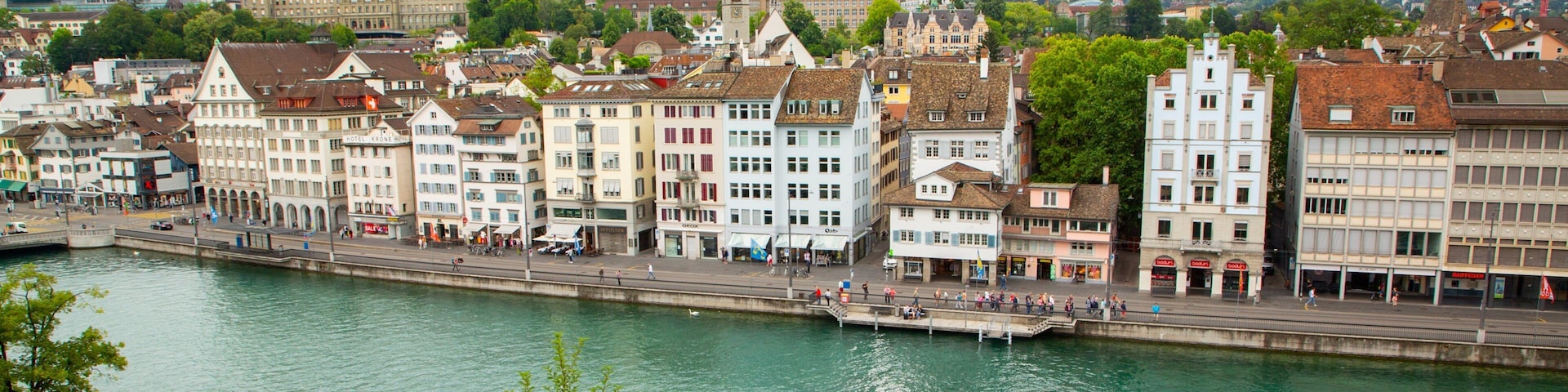 A river with a boat, surrounded by historic buildings and a prominent church spire.