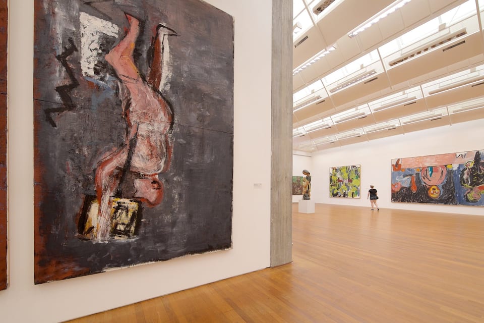 An art gallery with abstract paintings on the walls and a wooden floor.