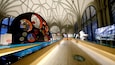 A museum interior with a large circular sculpture, wooden floors, and arched ceilings.