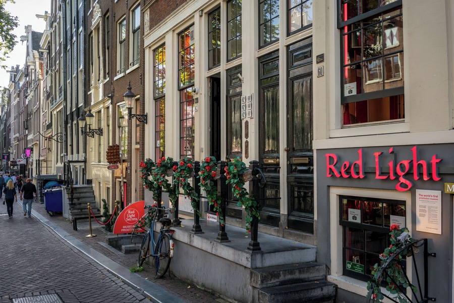 A street with buildings, a Red Light sign, and a bicycle.