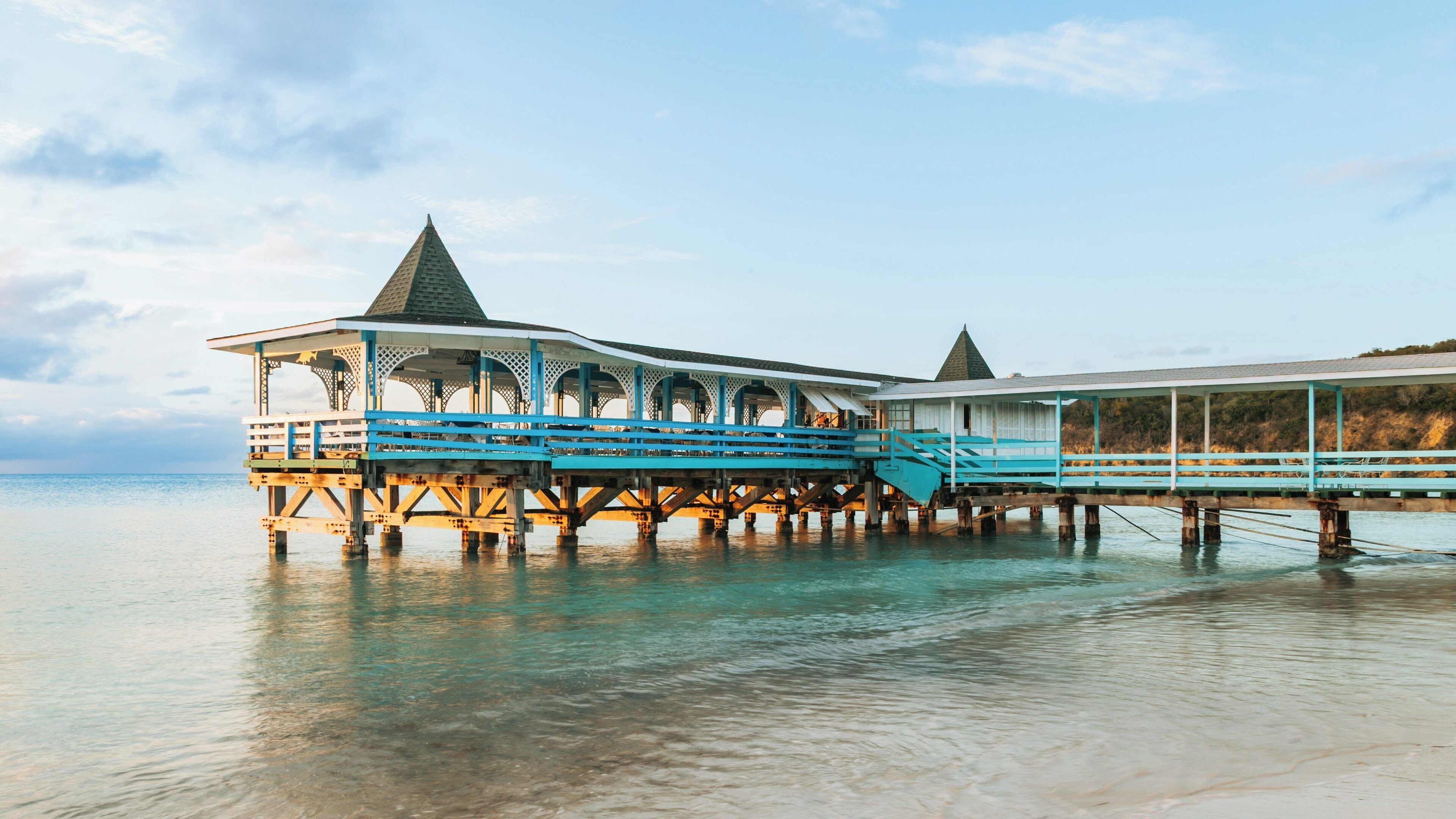 Explore the stunning beauty of Dickenson Bay Beach at Paradise View in St. John's, Antigua and Barbuda, featuring a charming pier and calm waters at sunset