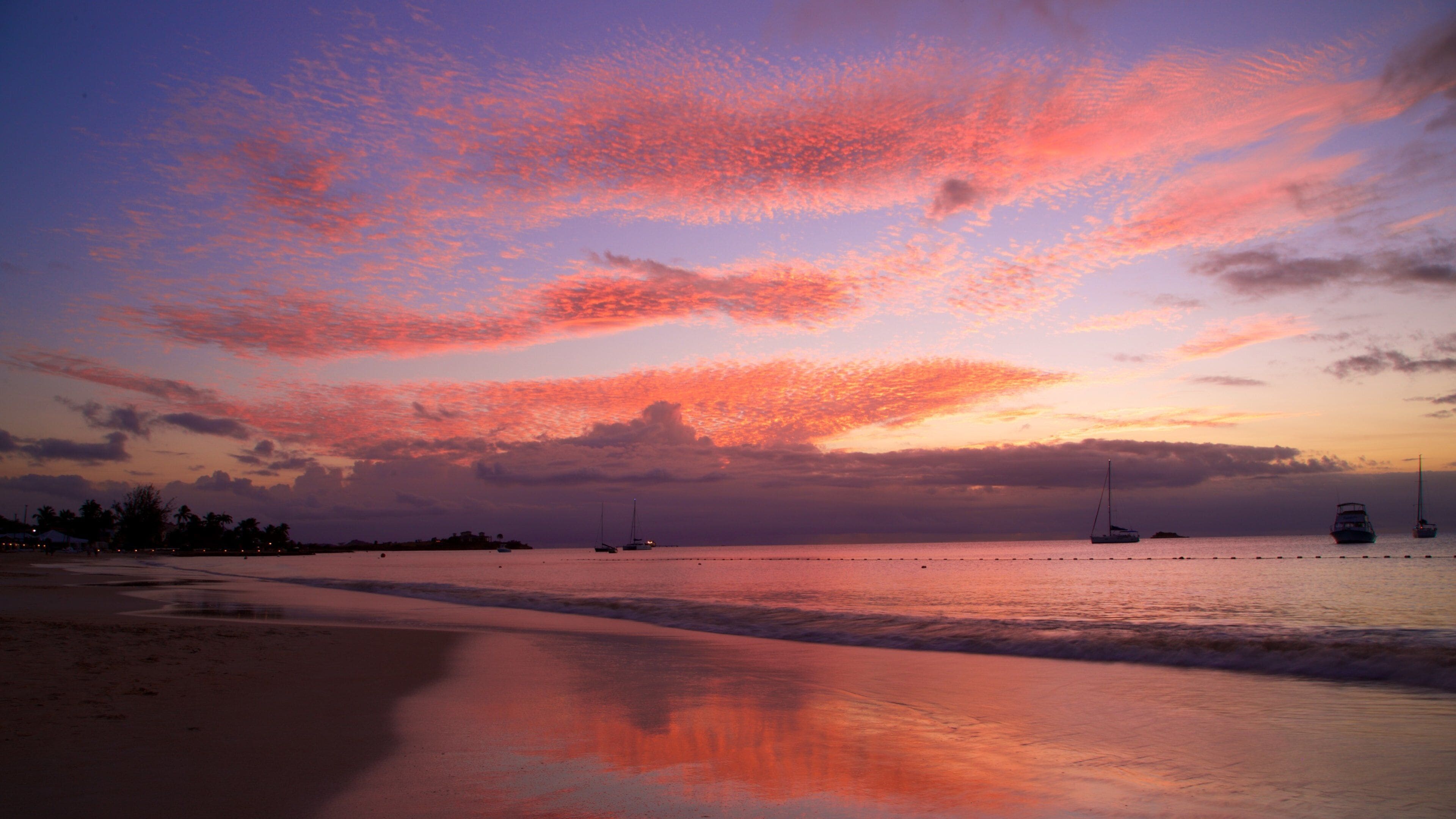 Dickenson Bay Beach featuring a sandy beach, a sunset and general coastal views