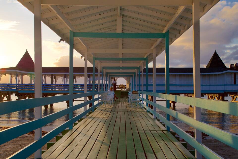 A wooden pier with a covered walkway leading to a building with a red roof.
