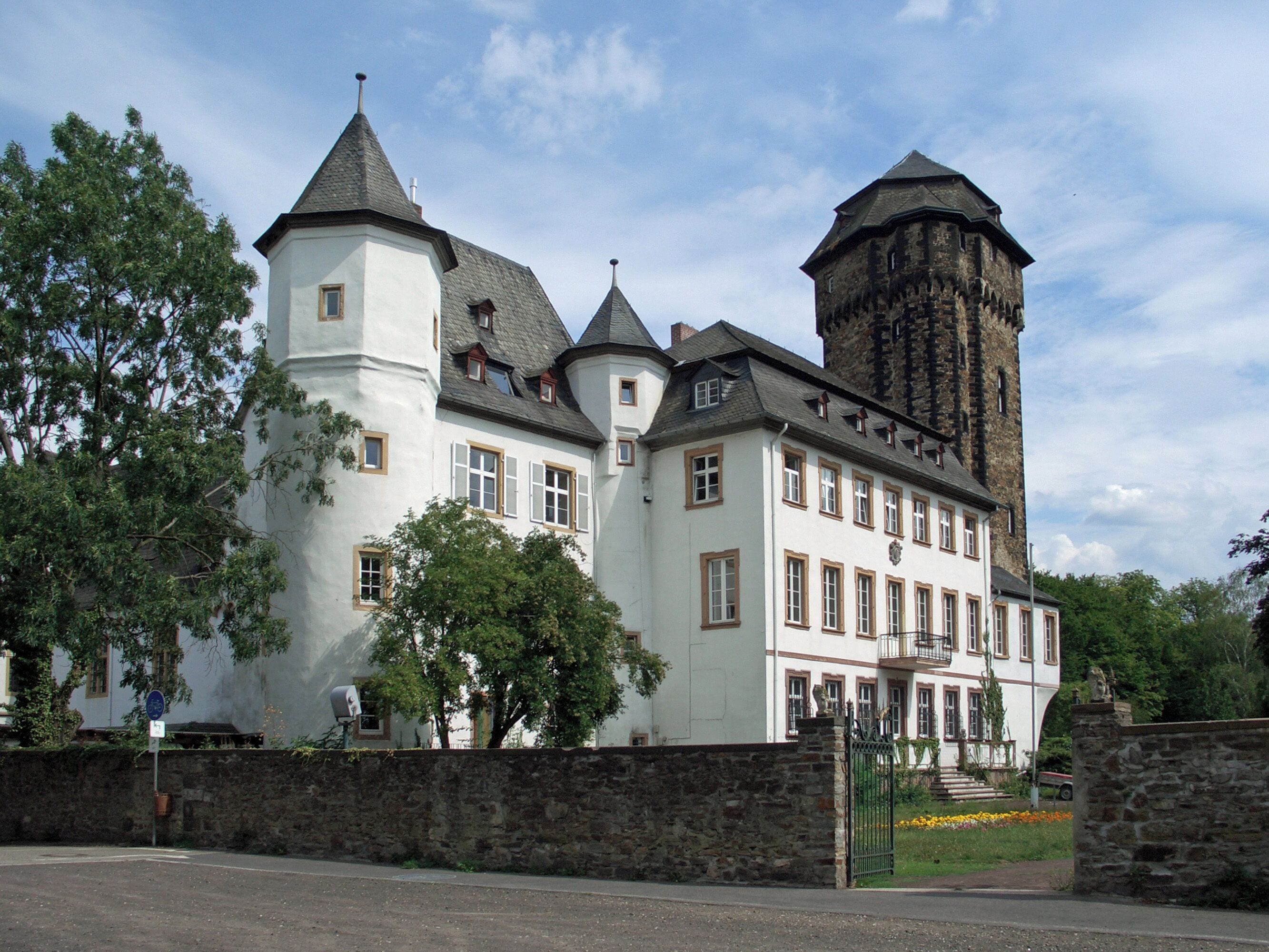 A large white building with multiple towers and a stone tower.