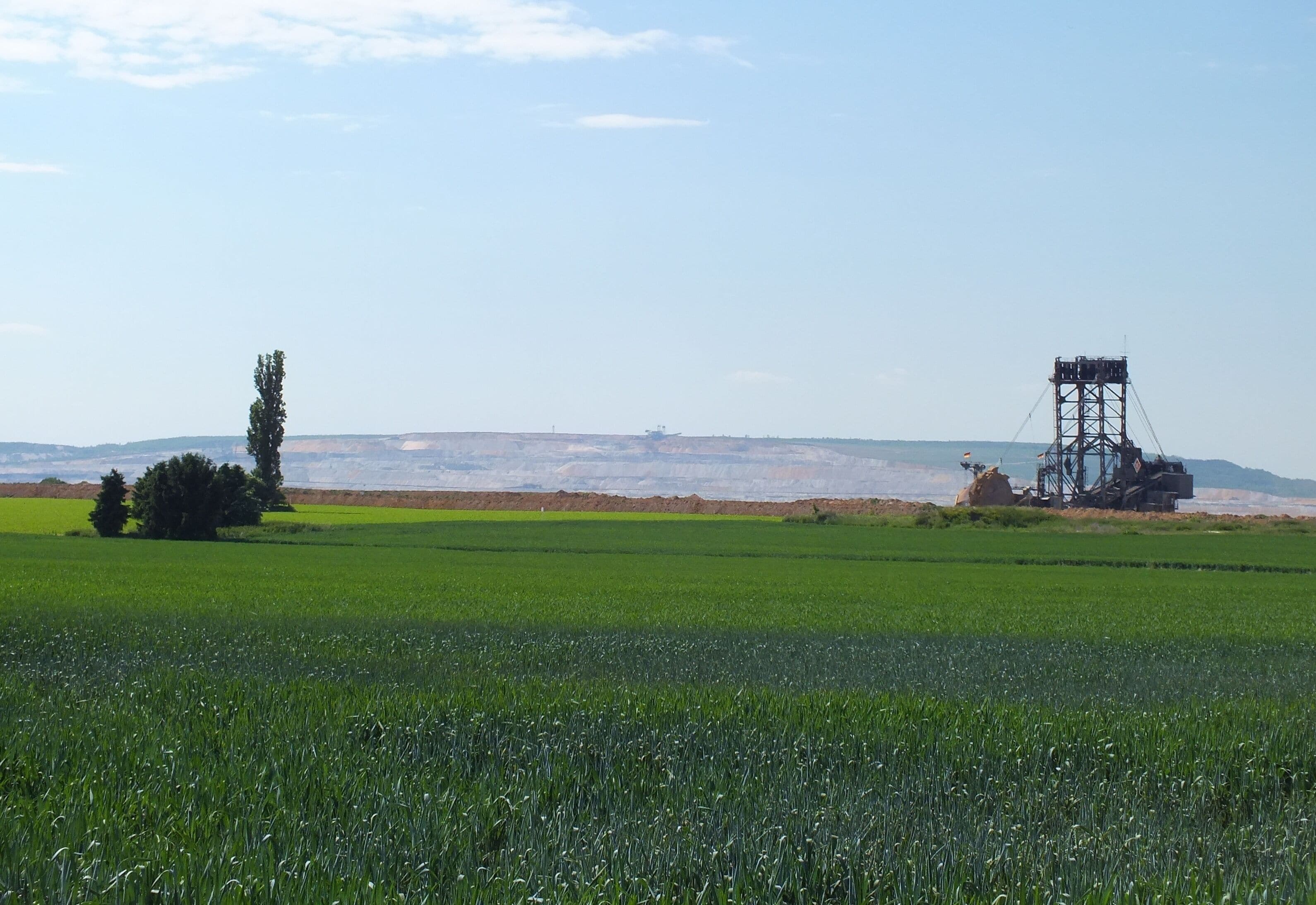 A green field with a mining structure and a tree.