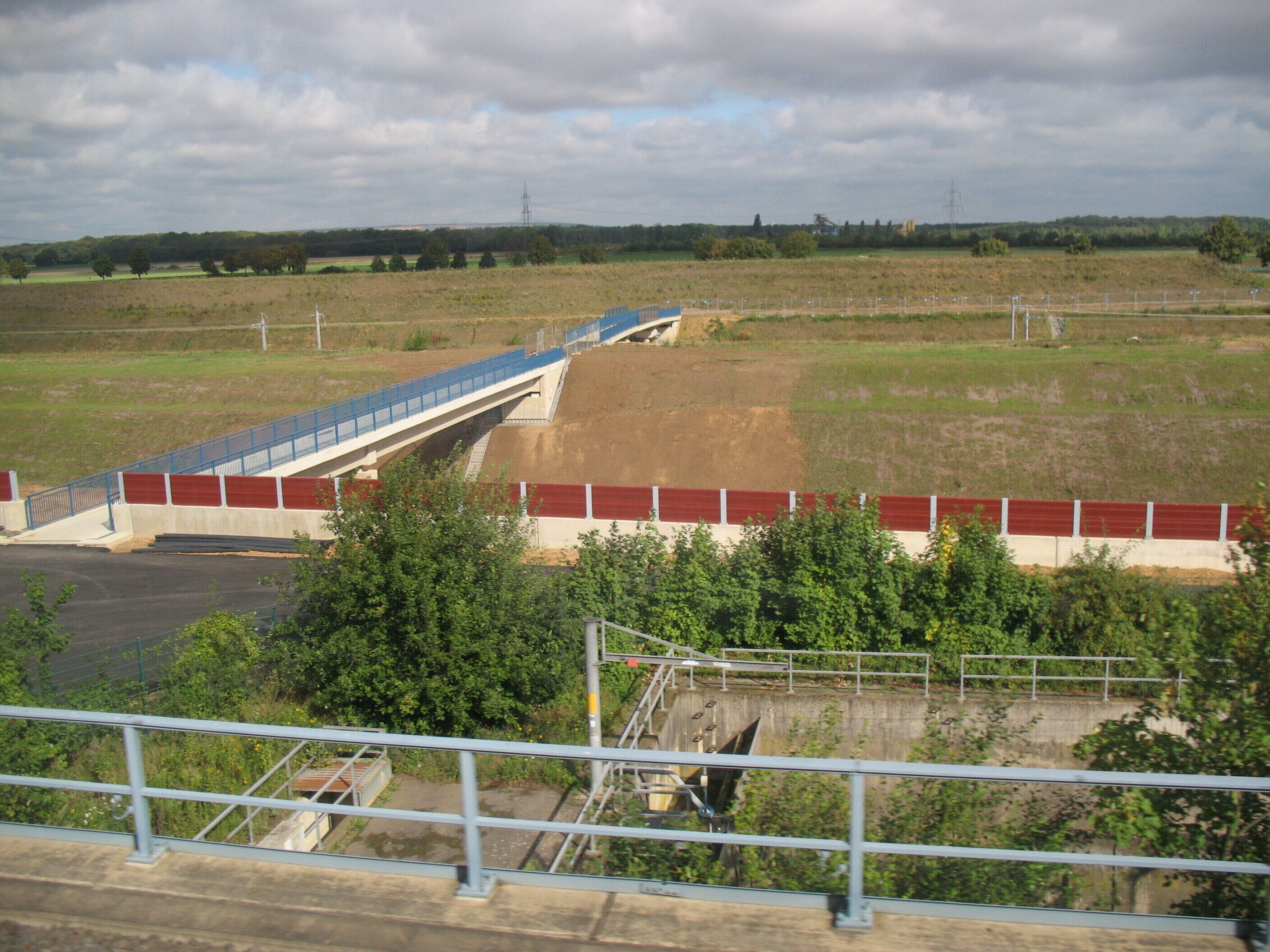 A bridge over a river, surrounded by fields and trees.