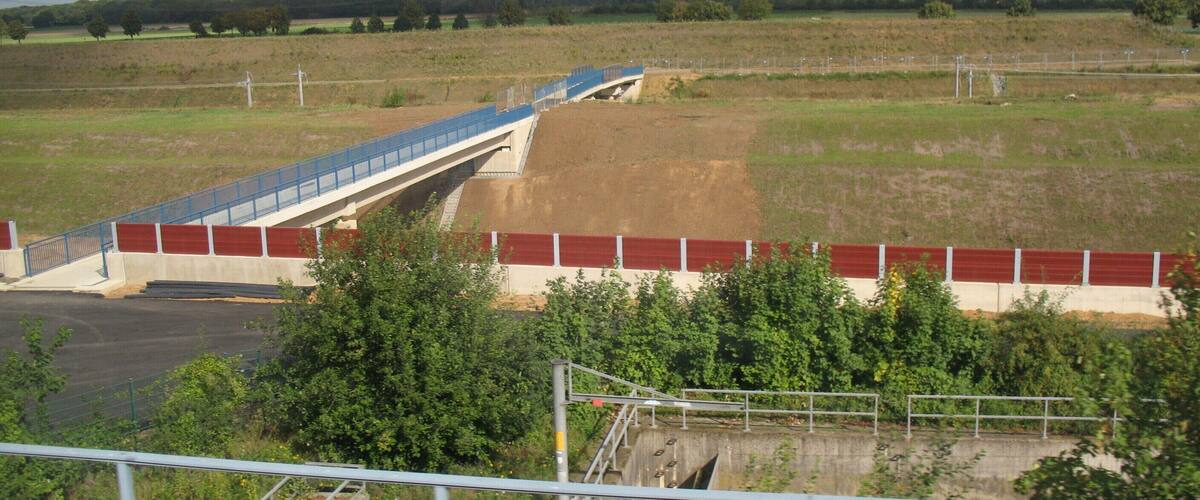 A bridge over a river, surrounded by fields and trees.