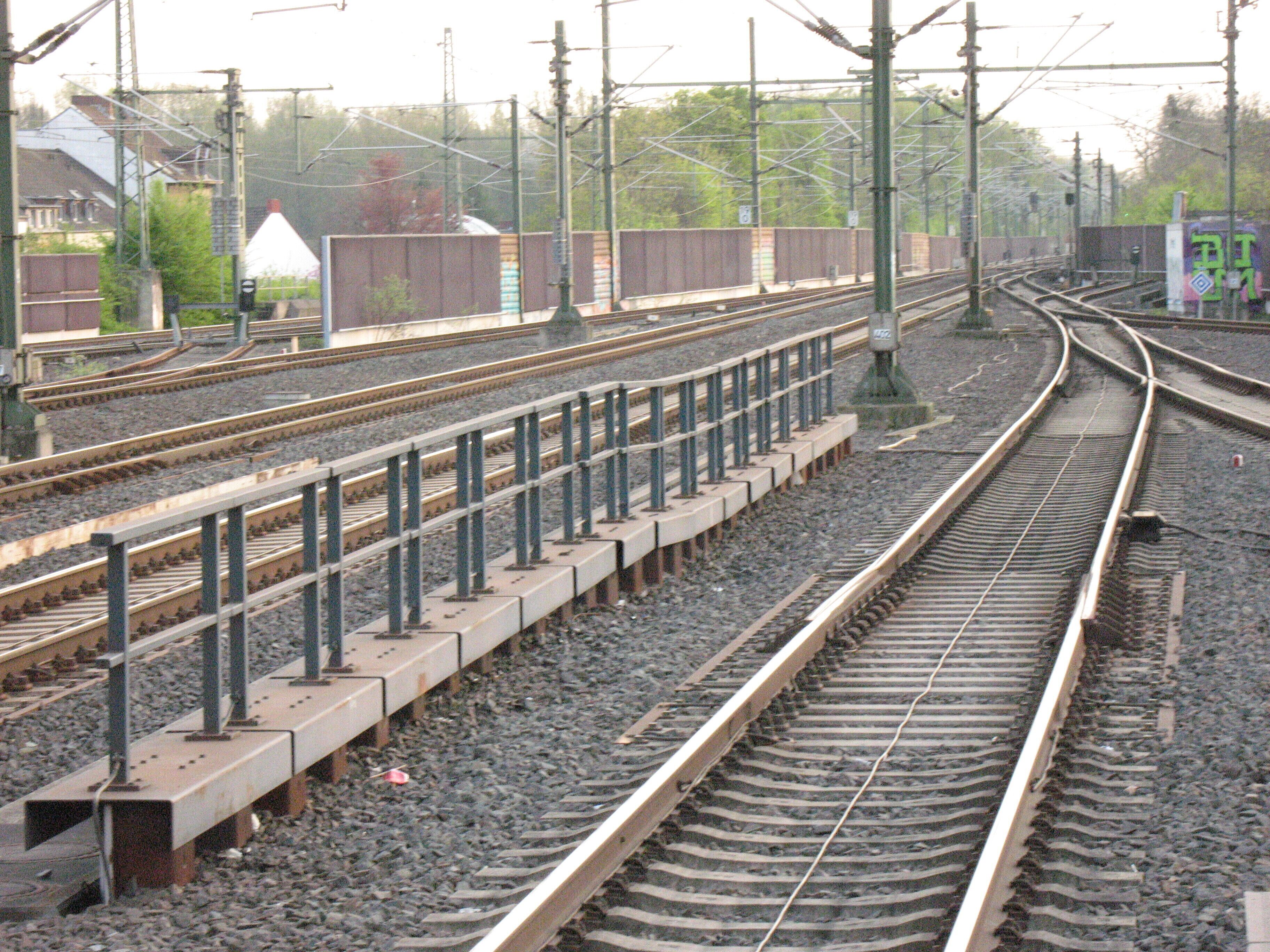 Railway tracks with multiple switches and overhead lines.