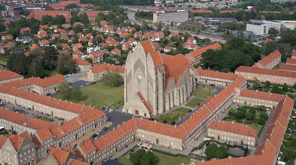 A cathedral with a tall spire, surrounded by residential buildings with red roofs.