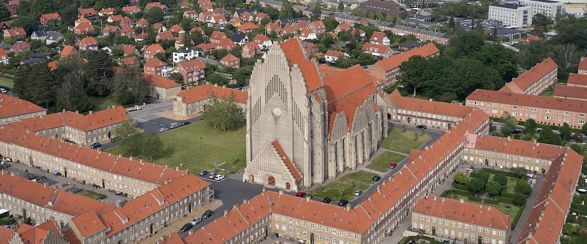 En katedral med et højt tårn, omgivet af boliger med røde tage.