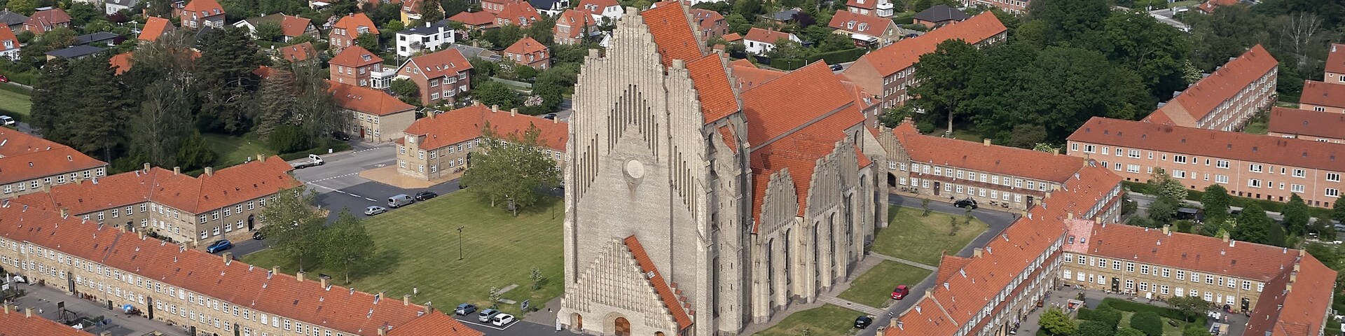 Una catedral con una aguja alta, rodeada de edificios residenciales con techos rojos.