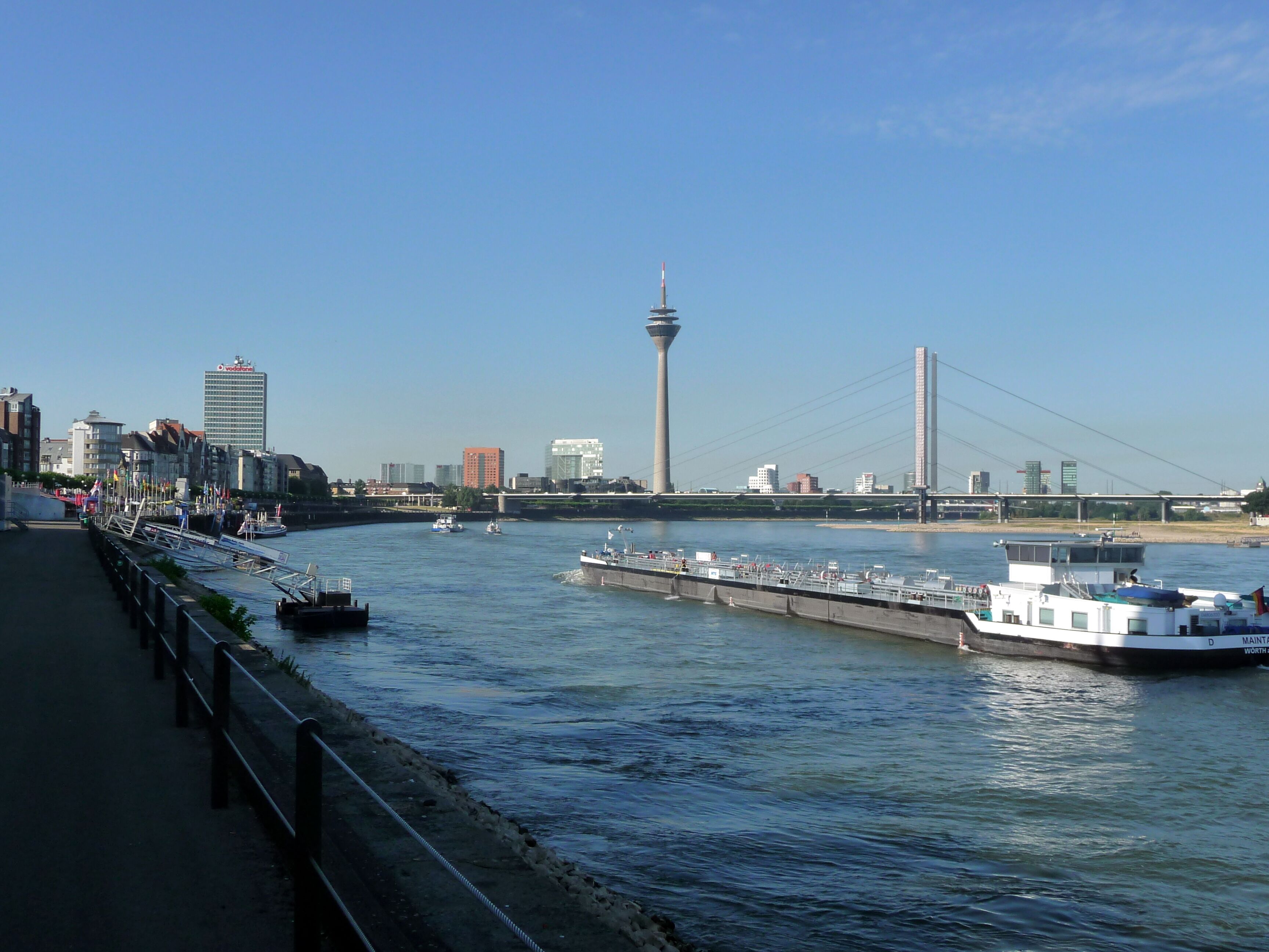 A river with boats, a bridge, and city buildings in the background.