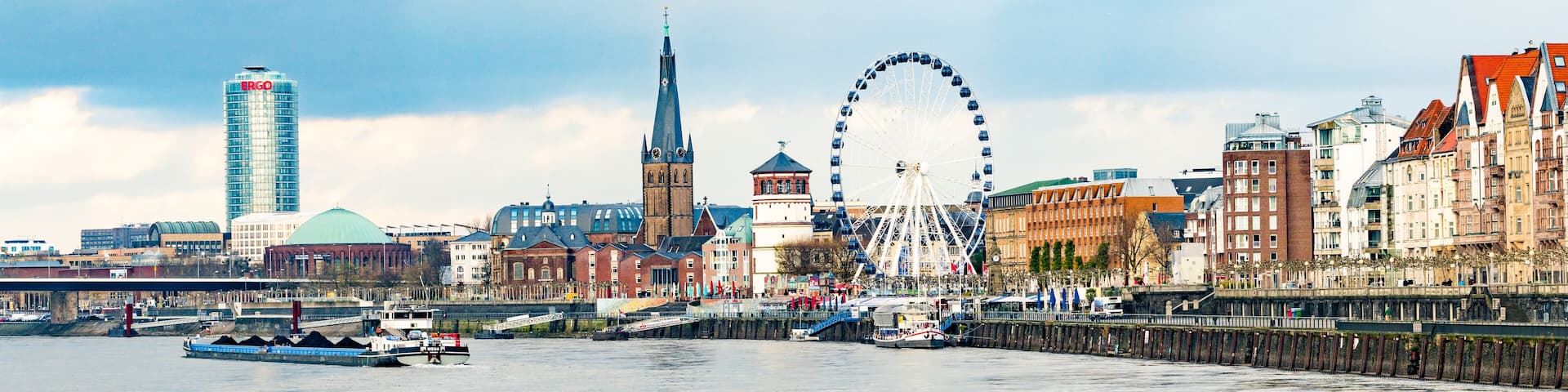 A city skyline with a modern skyscraper, a church spire, and a Ferris wheel.
