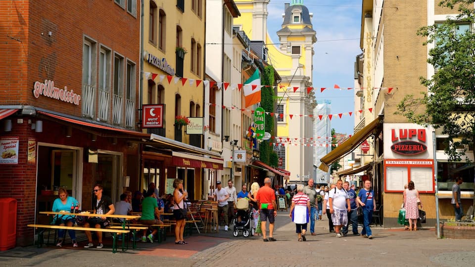 Een levendige straat met verschillende restaurants en winkels, waaronder een pizzeria en een pizzazaak.
