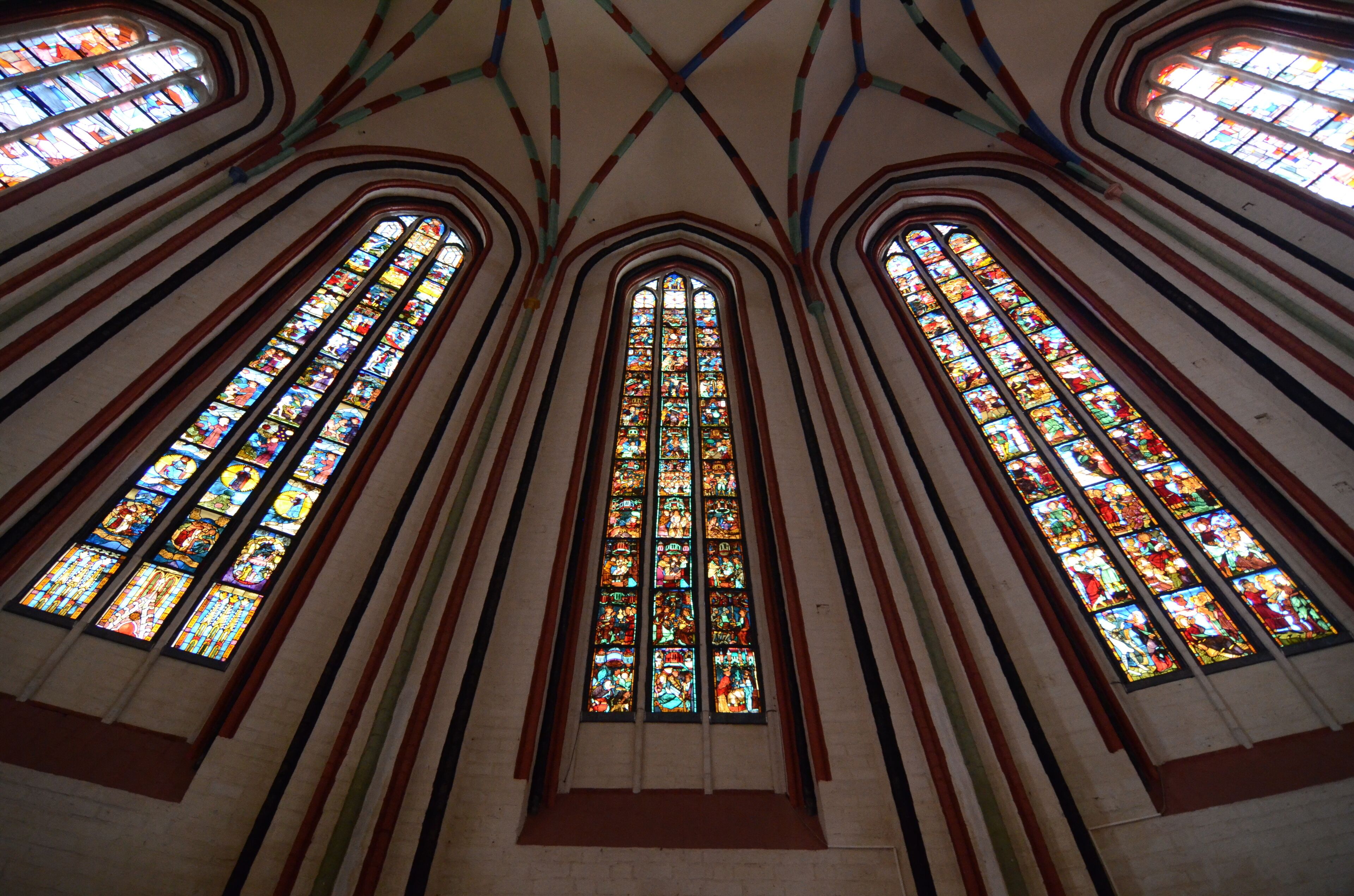 Interior de iglesia con altas vidrieras y techos abovedados.