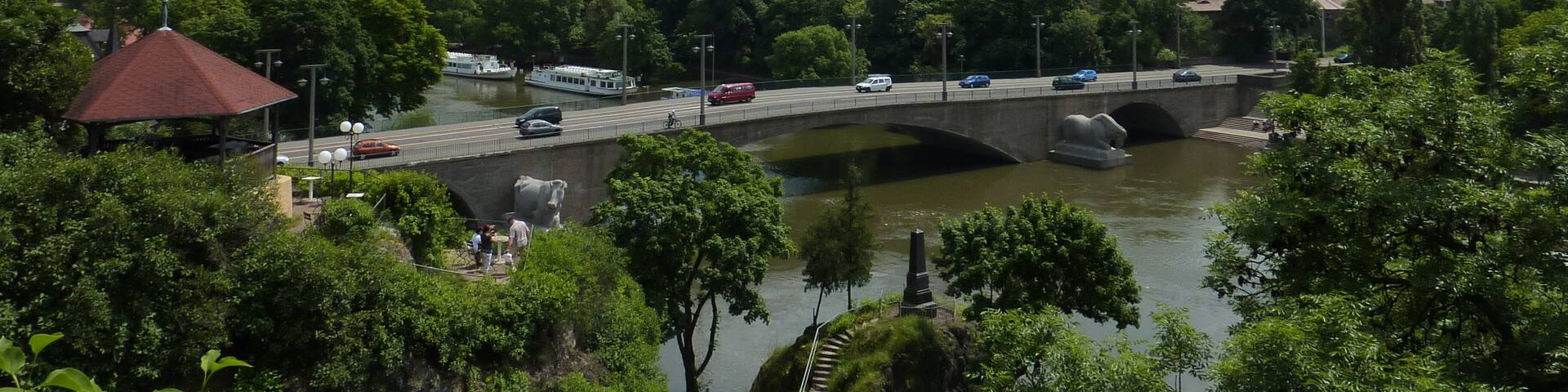 A river with a bridge, a tower, and lush greenery.