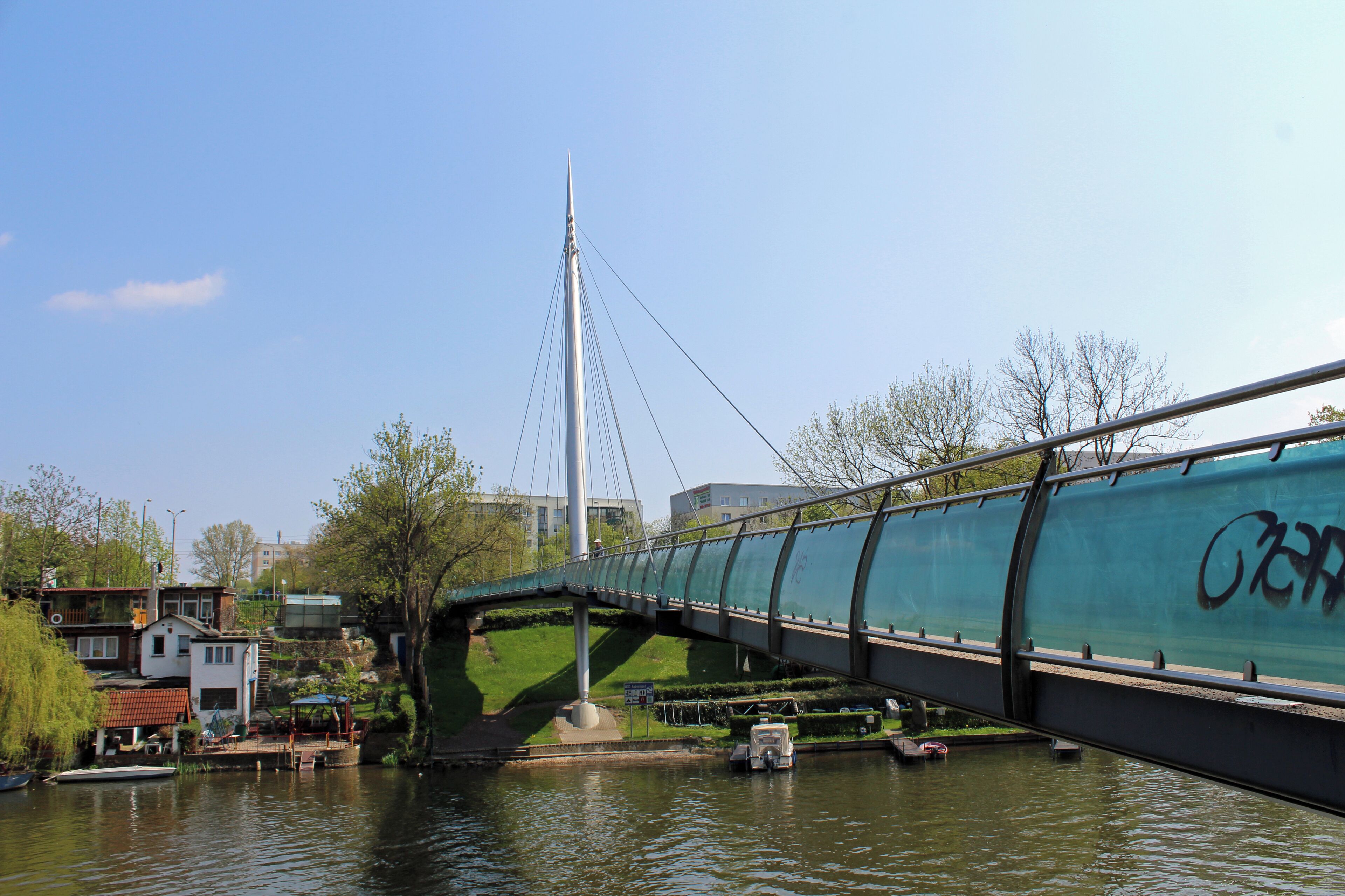 A bridge over a river with a cable-stayed structure, surrounded by buildings and greenery.