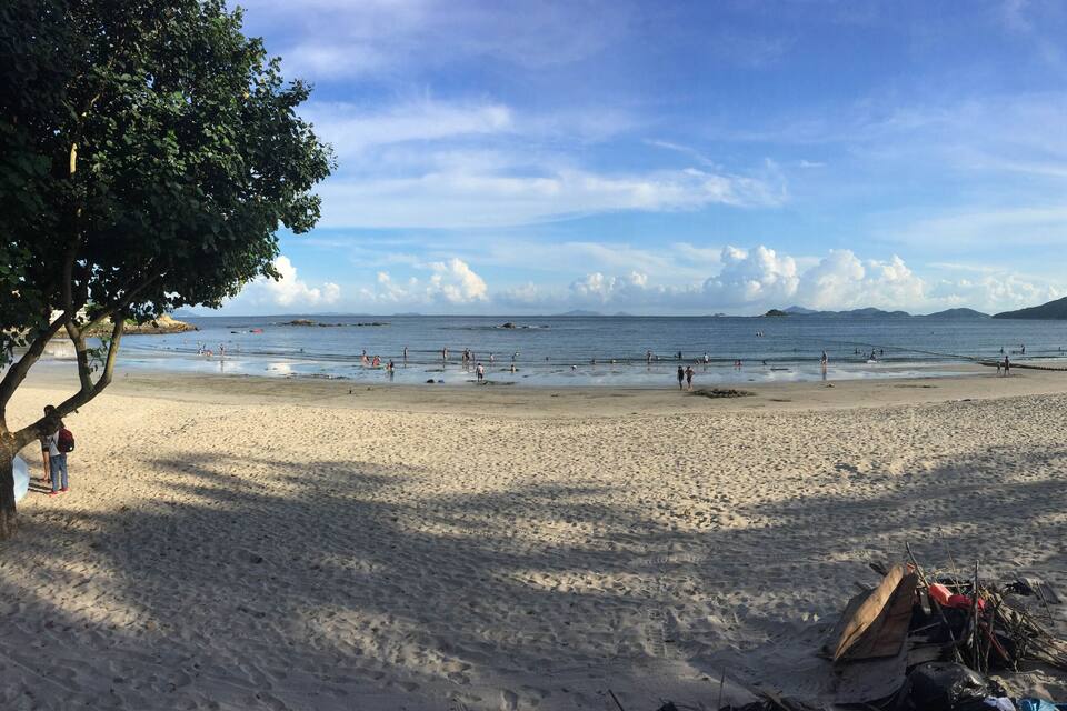 A sandy beach with footprints, a few people, and a clear sky.