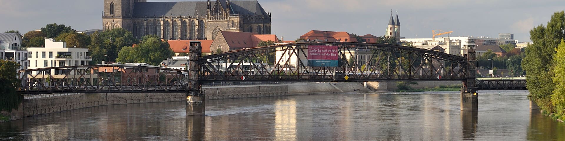 A historic bridge over a river with a prominent church and tower in the background.