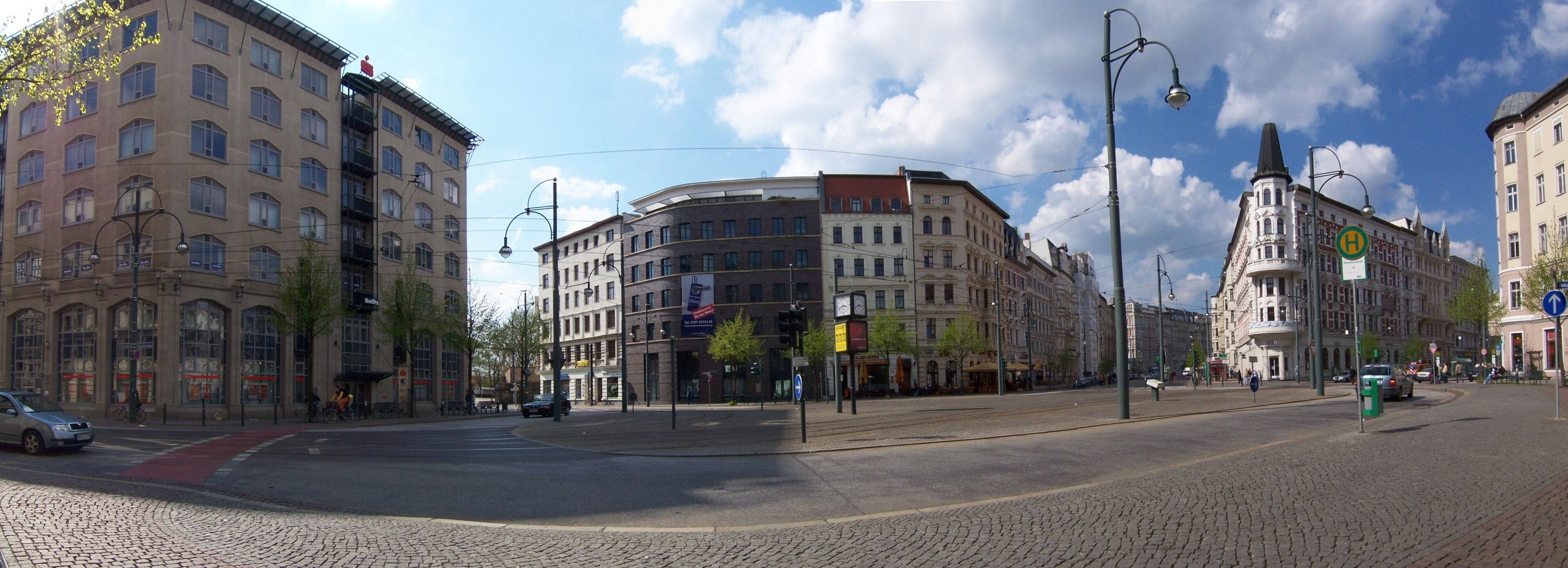 A cobblestone street with historic buildings, a tram line, and a clear blue sky.