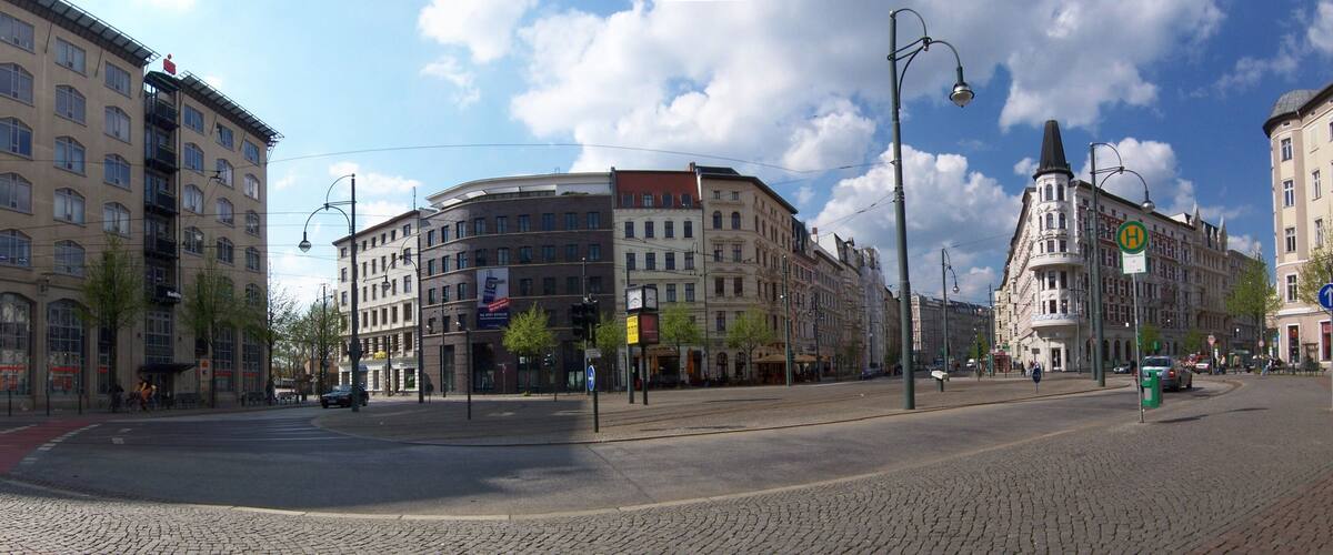 A cobblestone street with historic buildings, a tram line, and a clear blue sky.
