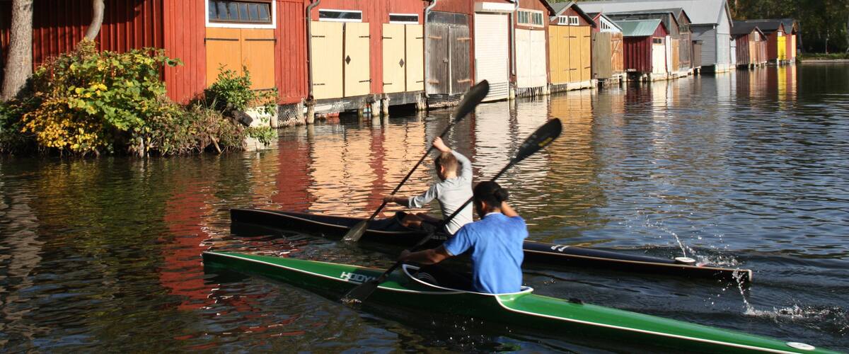 A canoe on a calm river with houses on the shore.