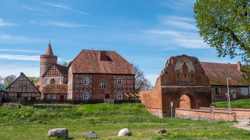 A historic church with a bell tower and a large brick building with a pointed arch.