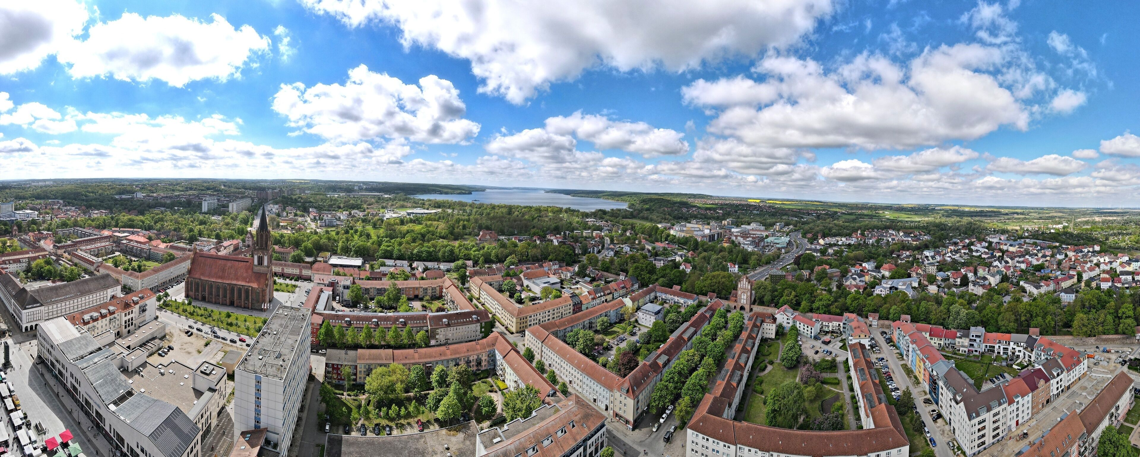 A panoramic view of a city with a prominent church, a river, and surrounding greenery.