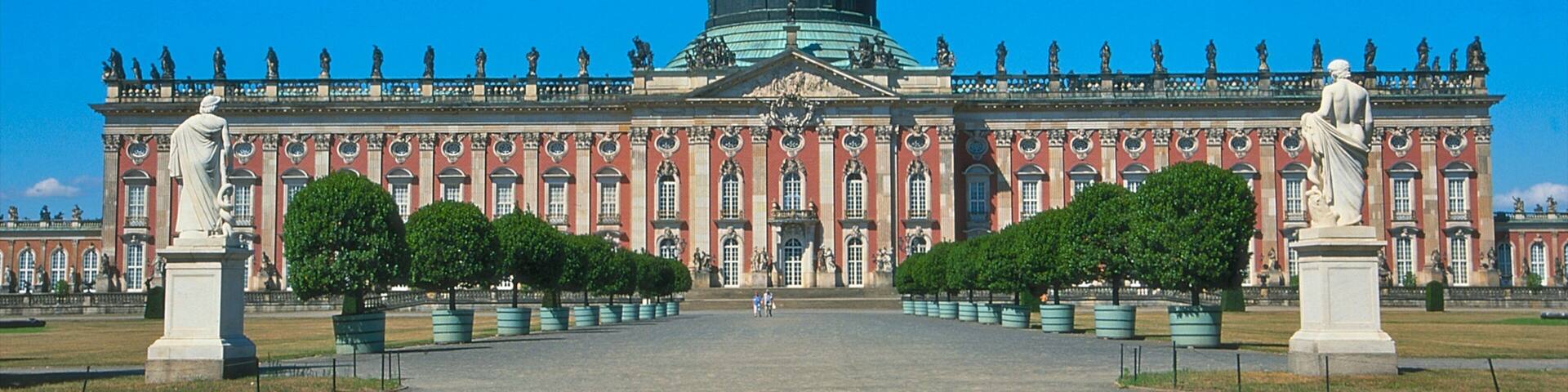 A grand palace with a large dome, symmetrical facade, and statues lining the front.